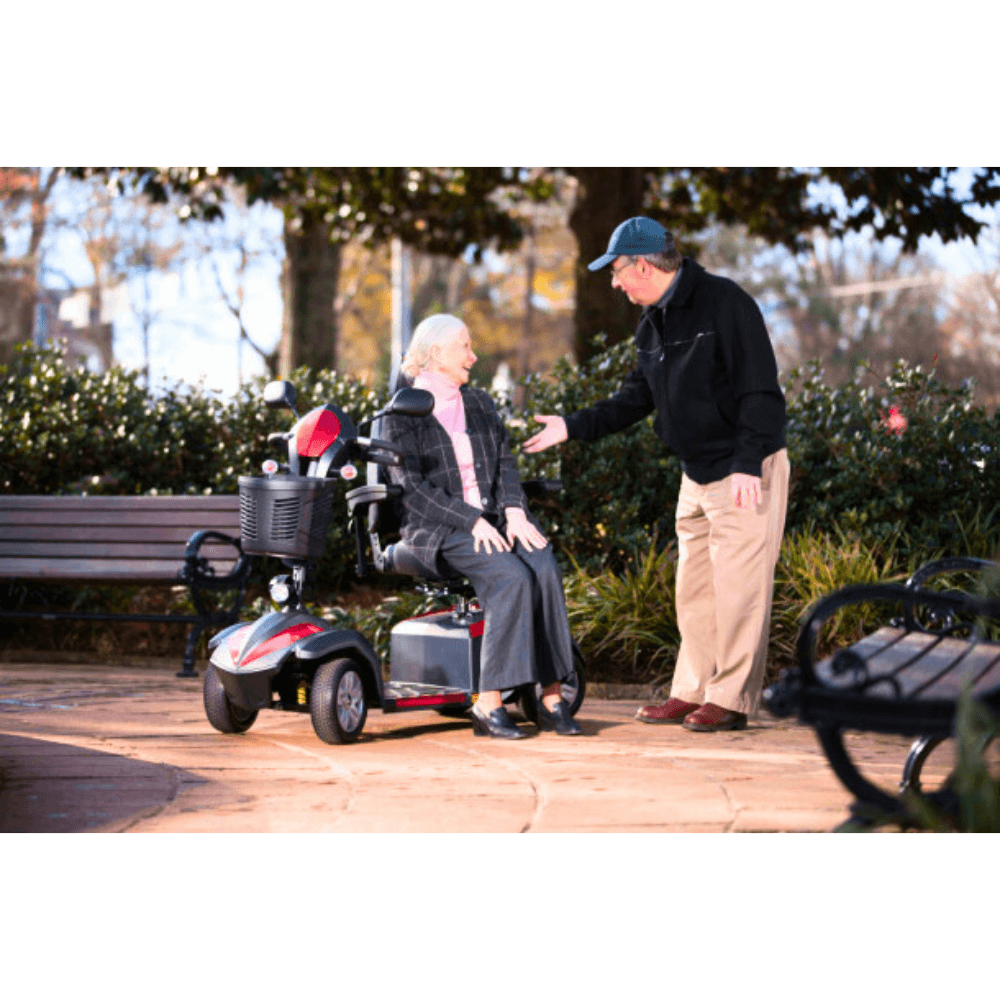 A Man Talking to an Elderly Woman Seated on the Drive Medical Ventura 4-Wheel Mobility Scooter in a Park