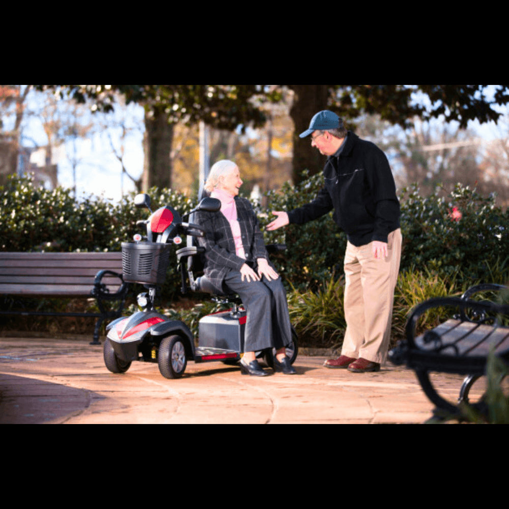 A Man Talking to an Elderly Woman Seated on the Drive Medical Ventura 4-Wheel Mobility Scooter in a Park