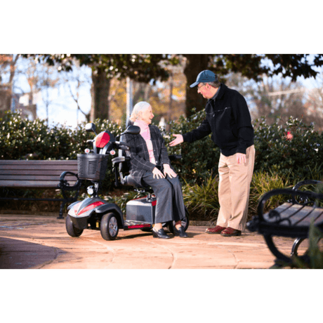 A Man Talking to an Elderly Woman Seated on the Drive Medical Ventura 4-Wheel Mobility Scooter in a Park